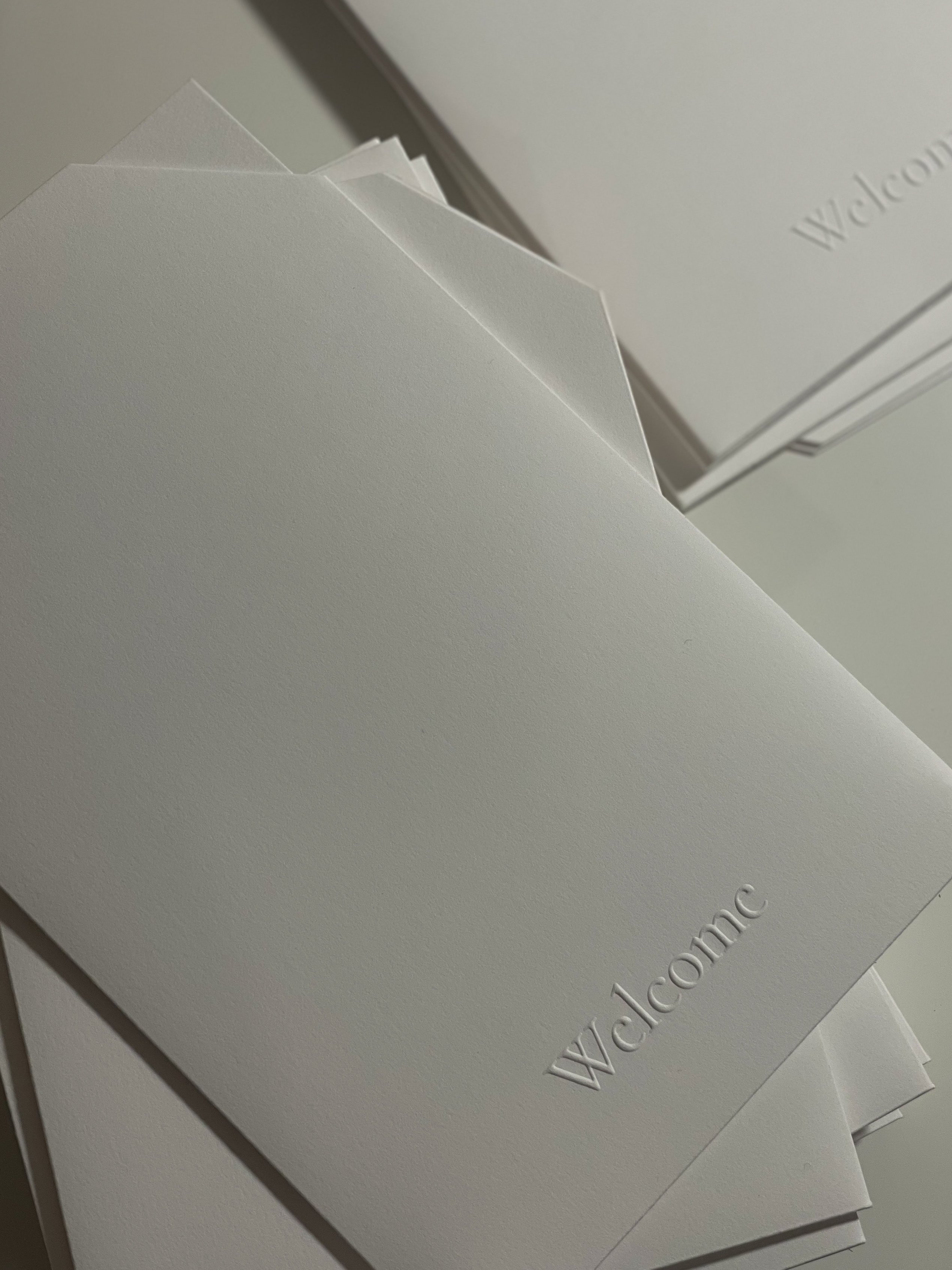 Blindgeprägte Willkommensmappen, gestapelt in weichem Licht
