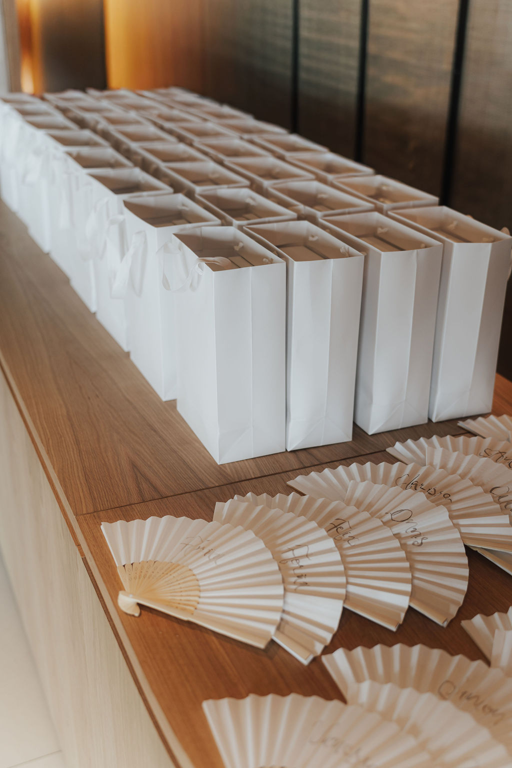Edle Gastgeschenktüten aus mattem Papier mit geprägtem Dankeschön und Henkeln aus italienischem Satinband, dazu kalligrafierte Fächer für die Gäste