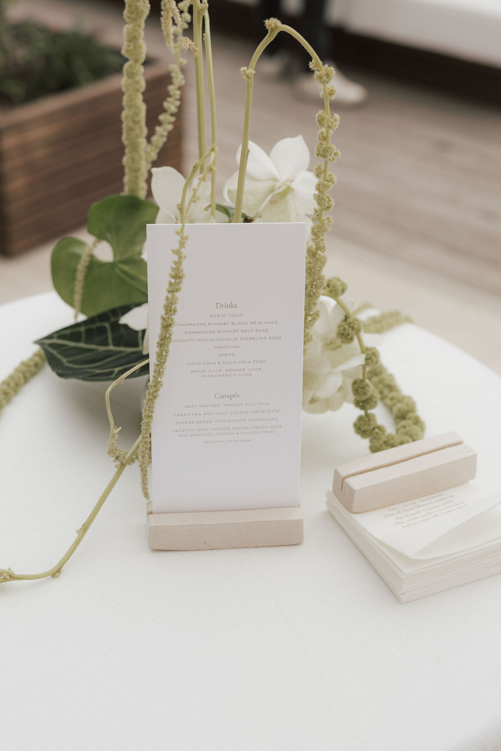 Cocktail- und Canapé-Karte im Letterpress auf Baumwollpapier in handgefertigtem Keramikhalter mit weißem Blumengesteck