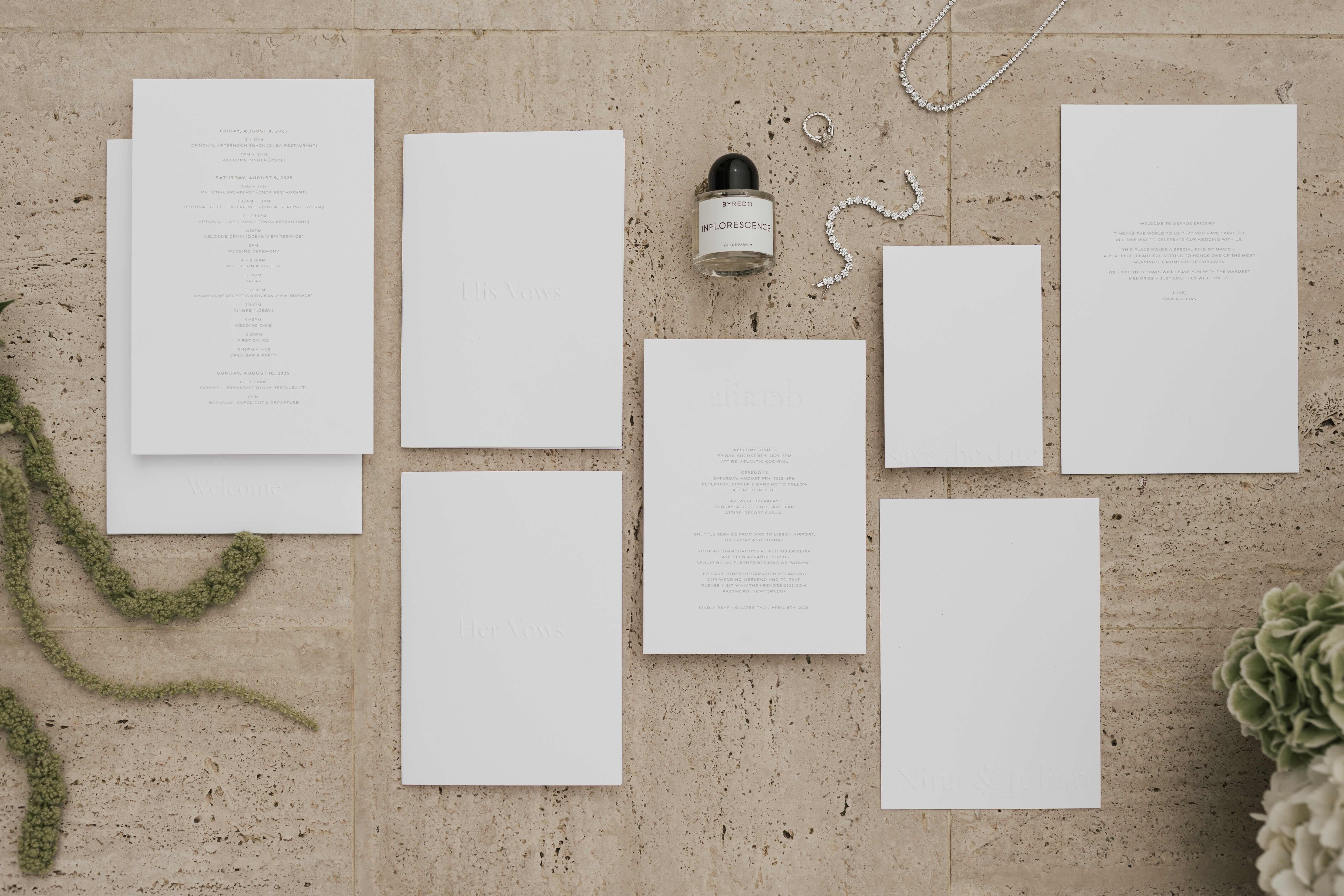 Flatlay des gesamten Papeterie-Sets auf Travertin — Wochenendprogramm im Letterpress auf Baumwollpapier, Hefte für das Eheversprechen, Willkommens-, Info- und RSVP-Karten, Nina und Julian